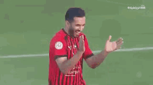 a soccer player in a red and black jersey is standing next to another player in a yellow jersey on a field .