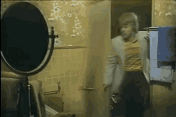 a man standing in a bathroom looking at himself in the mirror