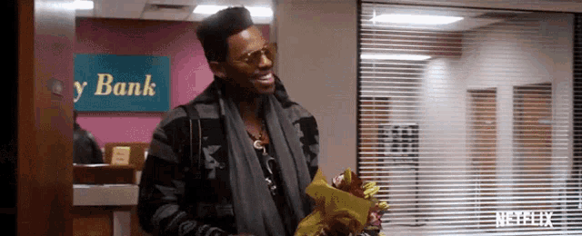 a man is holding a bouquet of flowers in front of a bank