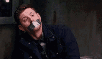 a man with duct tape on his mouth is wearing a tie and jacket .