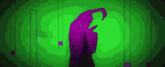 a purple and green silhouette of a person is dancing on a green background .