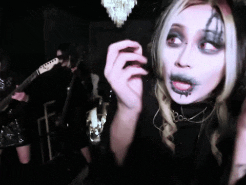 a woman with makeup on her face is playing a guitar in a band .