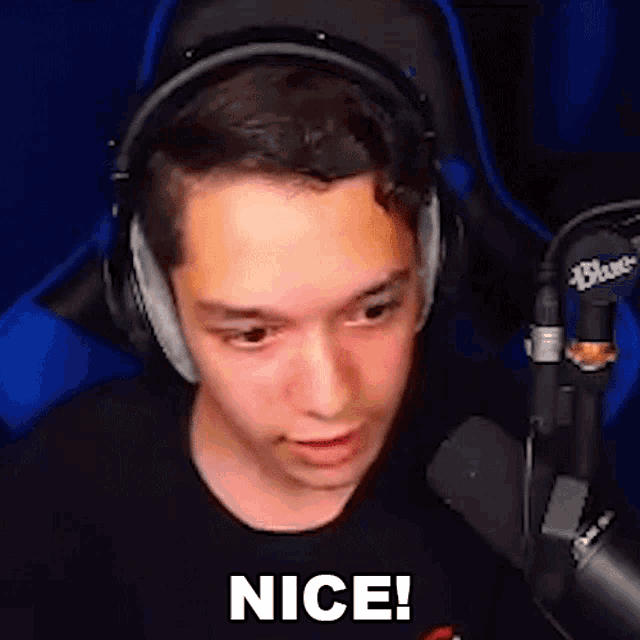 a young man wearing headphones and a black shirt is sitting in front of a microphone and saying `` nice '' .