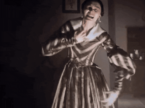 a woman in a striped dress is standing in a dark room