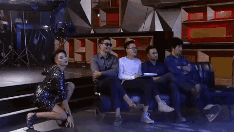 a group of people are sitting on a couch in a room and a woman is dancing on stage .