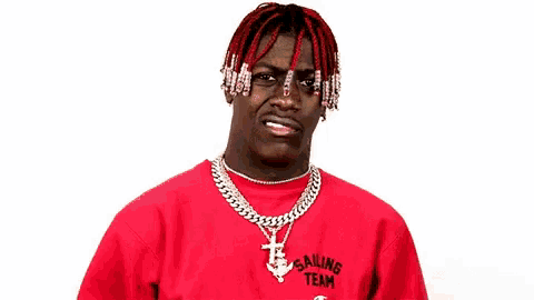 a man with red hair and dreadlocks is wearing a red sweater and a necklace .