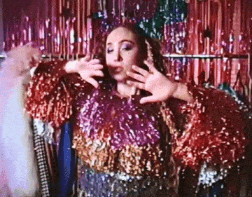 a woman is standing in front of a rack of clothes wearing a sequined top .