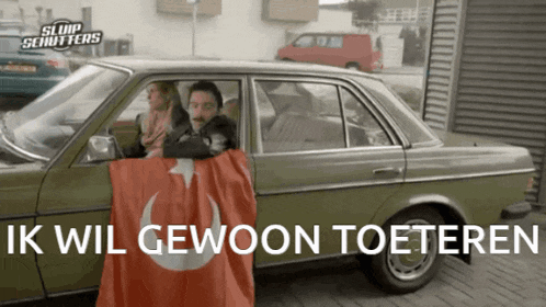 a man holding a flag in front of a car with ik wil gewoon toeteren written on it