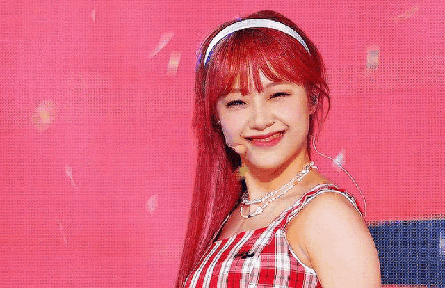 a woman with red hair is wearing a headband and a plaid dress .