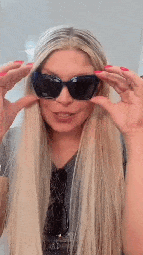 a woman is wearing sunglasses and making a funny face .