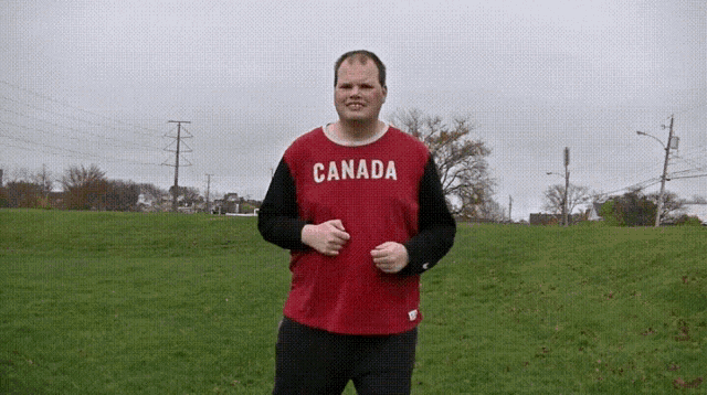 a man in a red canada shirt is running in a field