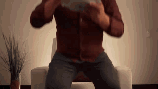a man in a red shirt is sitting in a chair playing a video game
