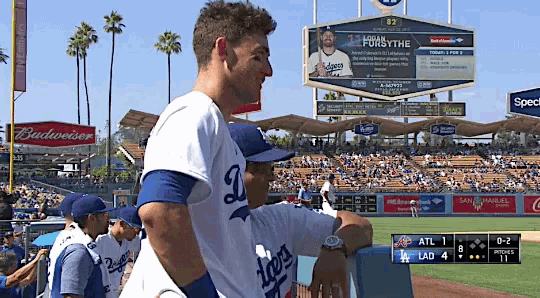 a dodgers player stands in front of a budweiser banner