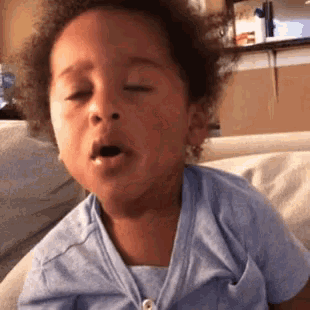 a little boy is sitting on a couch with his eyes closed .
