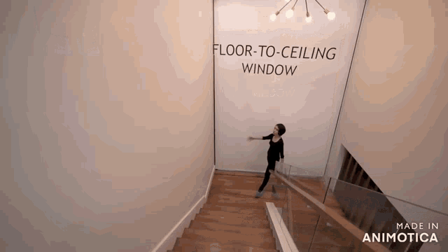 a woman is walking down a set of stairs in front of a sign that says floor-to-ceiling window