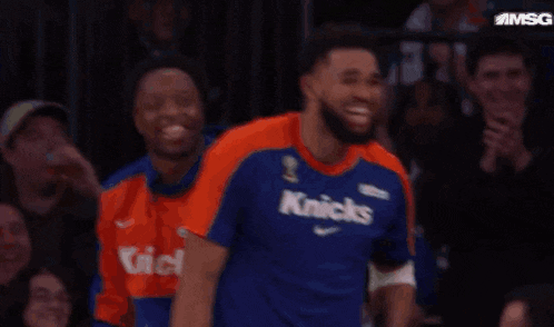 a man in an orange shirt is holding up a jersey that has the letter d on it