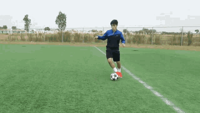 a man in a blue jacket is kicking a soccer ball