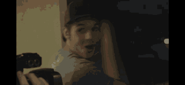 a man wearing a hat is holding a camera in his hand
