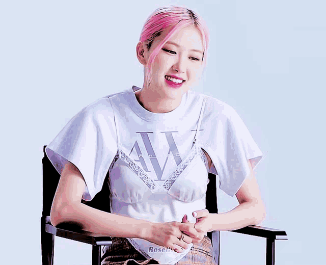 a woman with pink hair is wearing a white t-shirt with the letter w on the front
