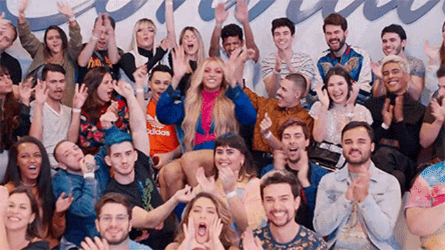 a large group of people are sitting in a room with their arms in the air .