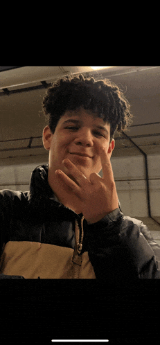 a young man wearing a black and tan jacket giving the middle finger