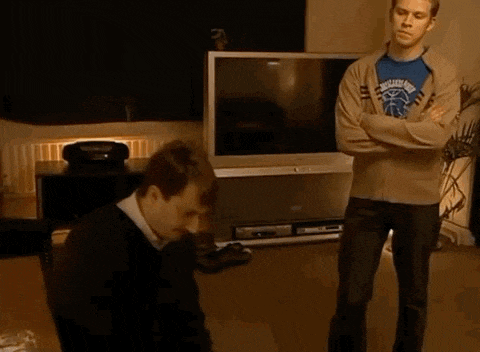 a man wearing a brooklyn nets shirt stands next to another man in a living room