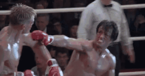 two men are fighting in a boxing ring with a referee watching .