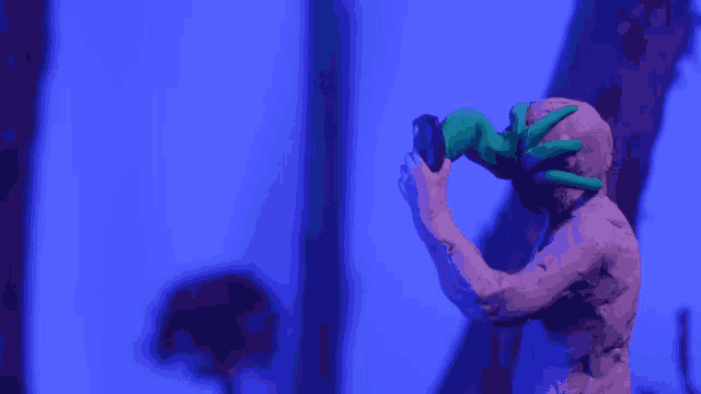 a statue of a man with a green hand holding a purple object