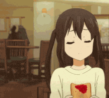 a girl with pigtails is holding a piece of bread with a heart on it .
