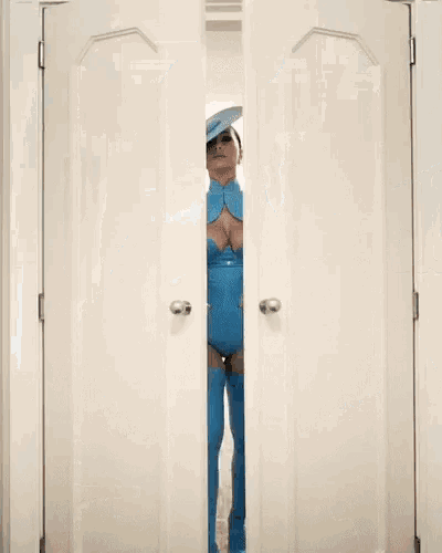 a woman in a blue outfit is walking through a door