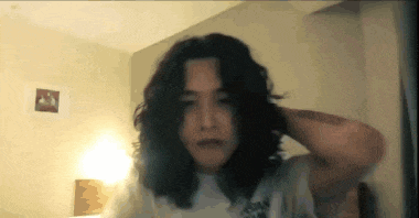a woman with curly hair is adjusting her hair
