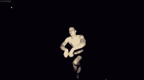 a shirtless man is dancing in the dark in a dark room .