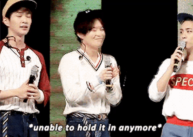 a group of young men standing next to each other holding microphones and one of them is wearing a spec shirt