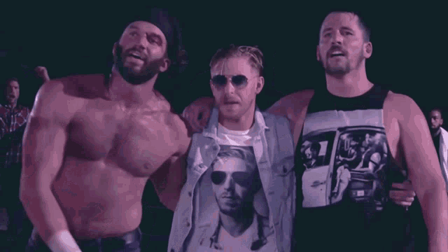 three men standing next to each other with one wearing a shirt with a picture of a man in sunglasses on it