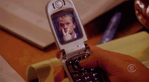 a person is holding a flip phone with a picture of neil on the screen .