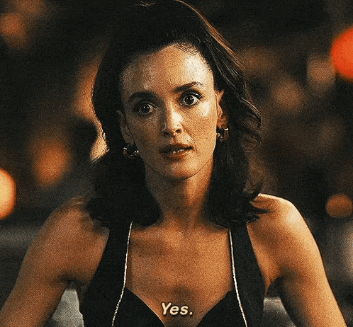a woman is wearing a black tank top with the word yes written on her chest .