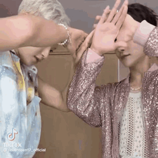 two men are giving each other a high five while wearing sequined jackets .
