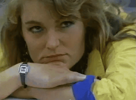 a woman wearing a watch and a yellow jacket is resting her chin on her hand .