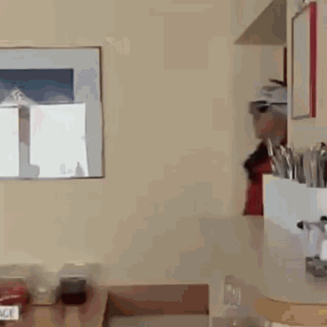 a man in a red jacket says " na ihr holzknie " while standing in a kitchen