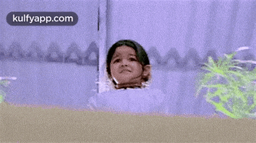 a little girl in a white dress is standing in front of a wall .