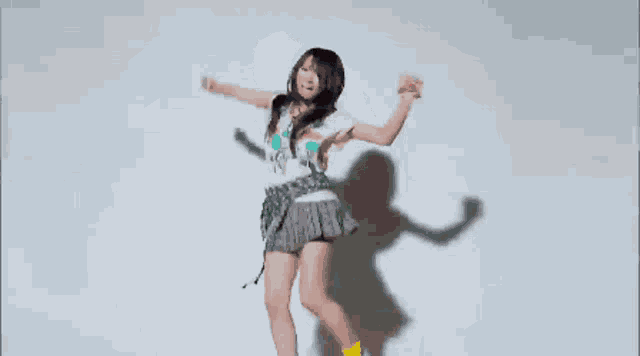 a woman in a black shirt and yellow shoes is jumping in the air against a white background .