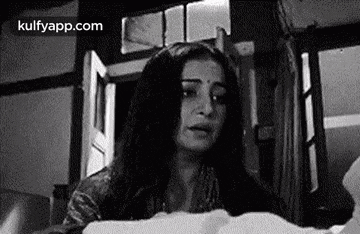 a woman is crying in a black and white photo while holding a piece of paper .
