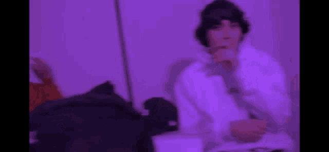 a blurry picture of a man smoking a cigarette in a room with purple lights .