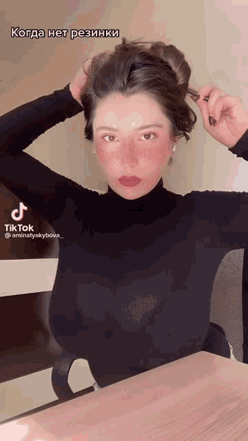 a woman in a black turtleneck holds her hair in a bun with a tiktok watermark