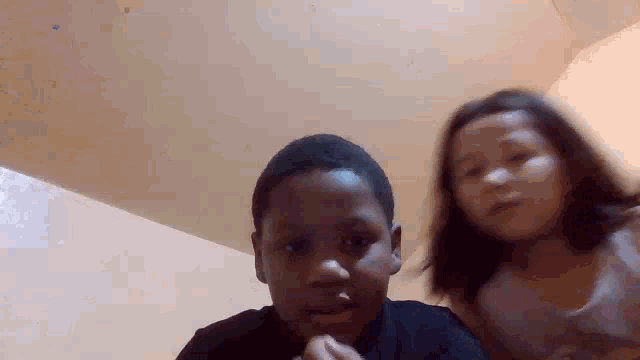 a boy and a girl are looking at the camera in a room .