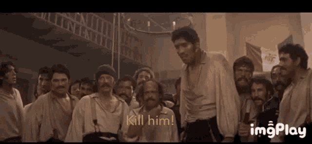 a group of men are standing in a room with the words `` kill him '' written on the bottom of the screen .
