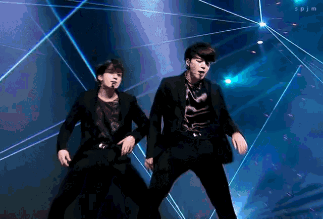 two men are dancing on a stage in front of a blue light .