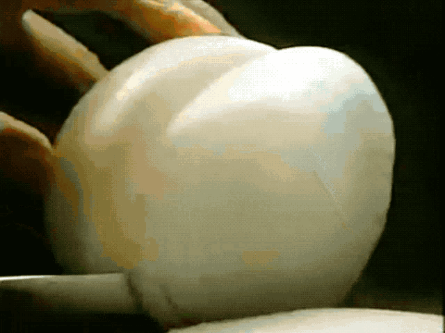 a close up of a person holding a white object with a black background