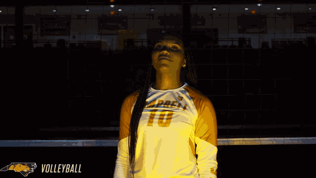 a woman in a tennessee volleyball jersey stands in front of a volleyball net