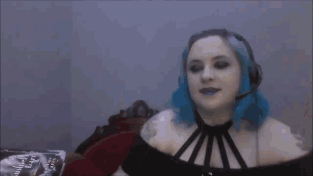 a woman with blue hair is wearing a headset while sitting in a chair